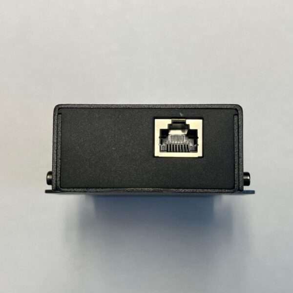 Ein schwarzes elektronisches Gerät, von vorne betrachtet, mit einem einzigen Ethernet-Anschluss in der Mitte. Das Gerät hat eine glatte, matte Oberfläche mit minimalen sichtbaren Markierungen. Es befindet sich auf einem hellgrauen Hintergrund, der seine kompakte Größe und rechteckige Form hervorhebt.