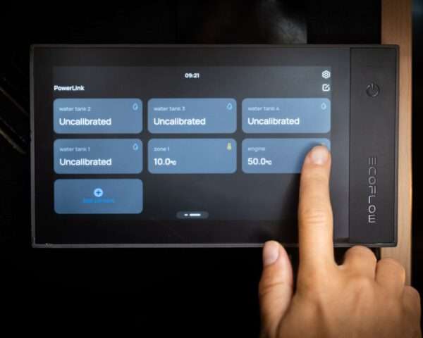 Ein digitales Touchscreen-Display dass die verschiedenen Sensormesswerte des PowerLink zeigt. Vier Wassertanks sind als nicht kalibriert aufgeführt, und eine Zone zeigt eine Temperatur von 10,0 °C an. Die Motortemperatur wird mit 50,0 °C angezeigt. Ein Zeigefinger in der Nähe des Bildschirms zeigt die Interaktion des Benutzers an, und unten befindet sich eine Option zum Hinzufügen von Sensoren. Die gesamte Benutzeroberfläche ist modern und schlank und steht vor einem dunklen Hintergrund.