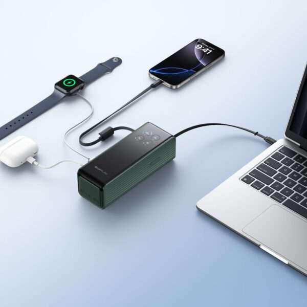 Eine elegante, moderne elektronische Ladestation steht auf einer hellblauen Fläche und ist mit verschiedenen Geräten verbunden. Ein Smartphone, das die Uhrzeit anzeigt, ist über ein Kabel angeschlossen, während eine Apple Watch in der Nähe aufgeladen wird. Weiße kabellose Ohrstöpsel sind ebenfalls an die Ladestation angeschlossen. Die Station hat ein kompaktes Design mit Tasten auf der Oberseite und ist in einer dunkelgrünen Farbe gehalten, die neben einem silbernen Laptop steht.
